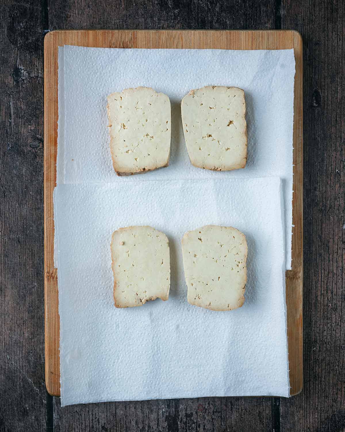 Slices of tofu on sheets of kitchen paper.