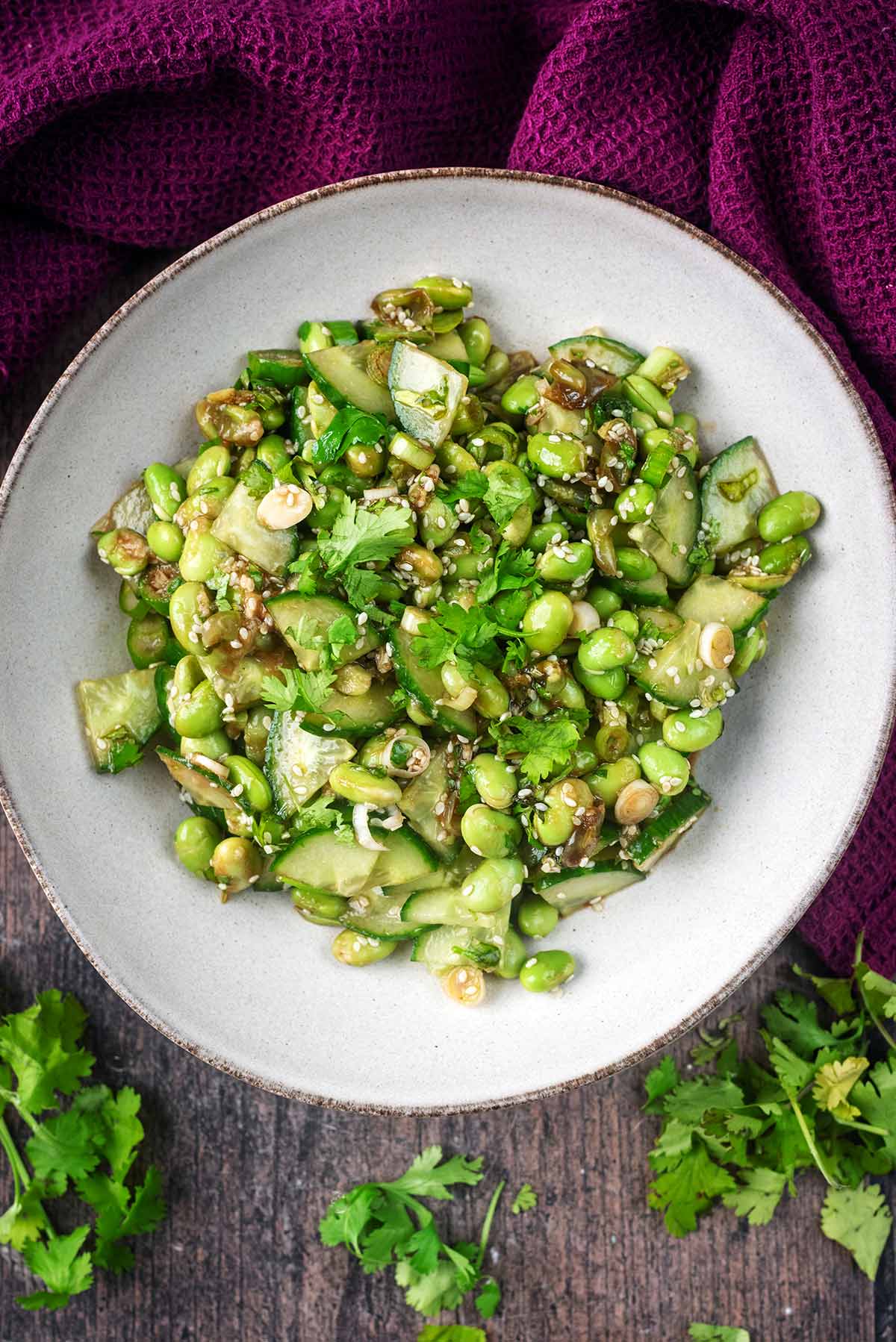 A bowl of sliced cucumber and edamame beans in a soy sauce dressing.