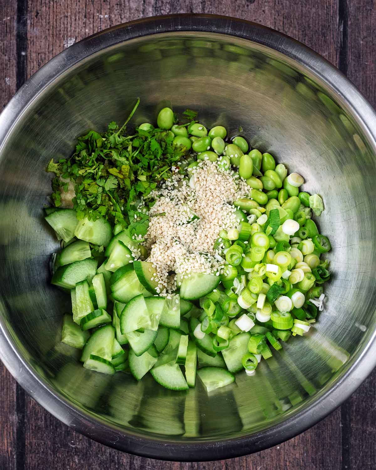 Edamame beans, sliced cucumber, spring onions, chopped coriander and sesame seeds in a large bowl.