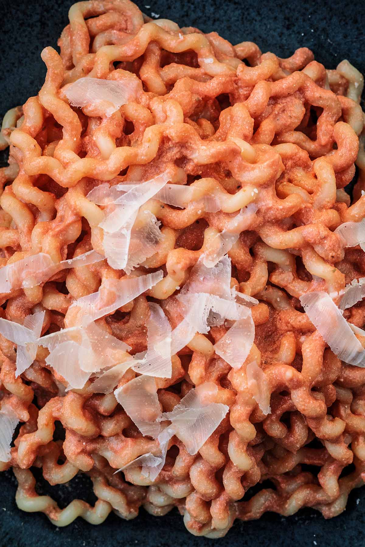 Cooked spiral shaped pasta coated in a creamy tomato sauce and topped with shaved Parmesan.
