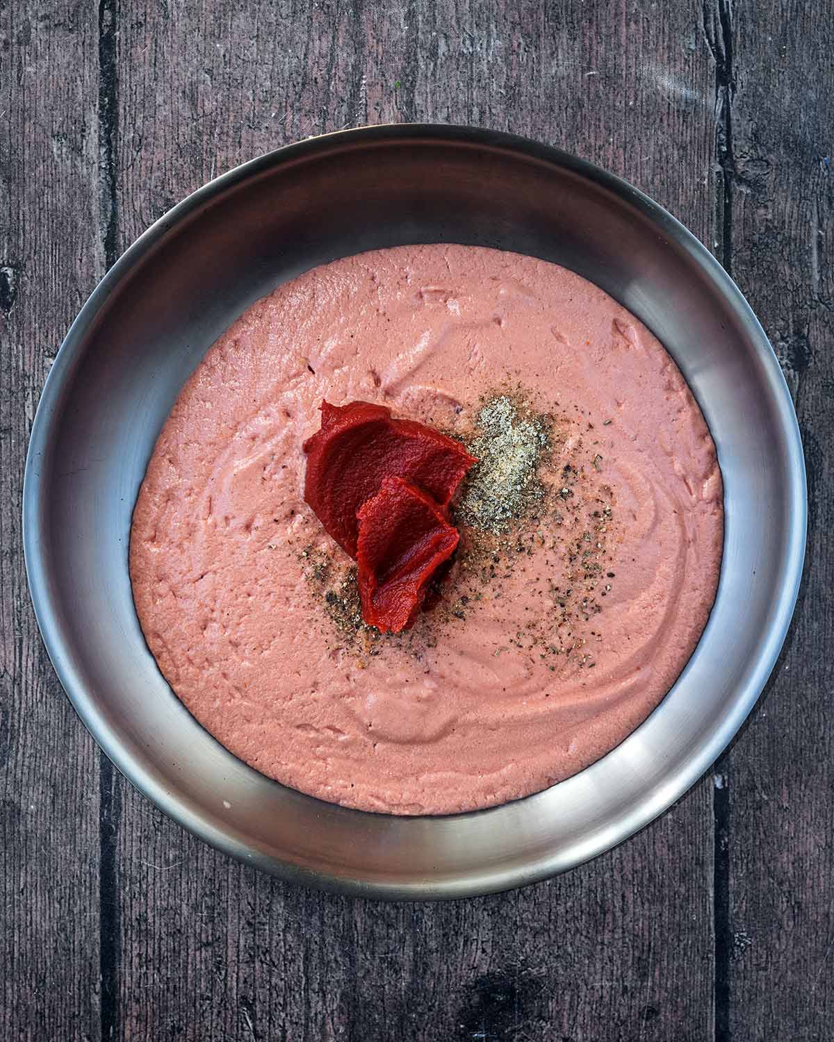 The tomato and cheese mixture in a pan with tomato puree and seasoning.