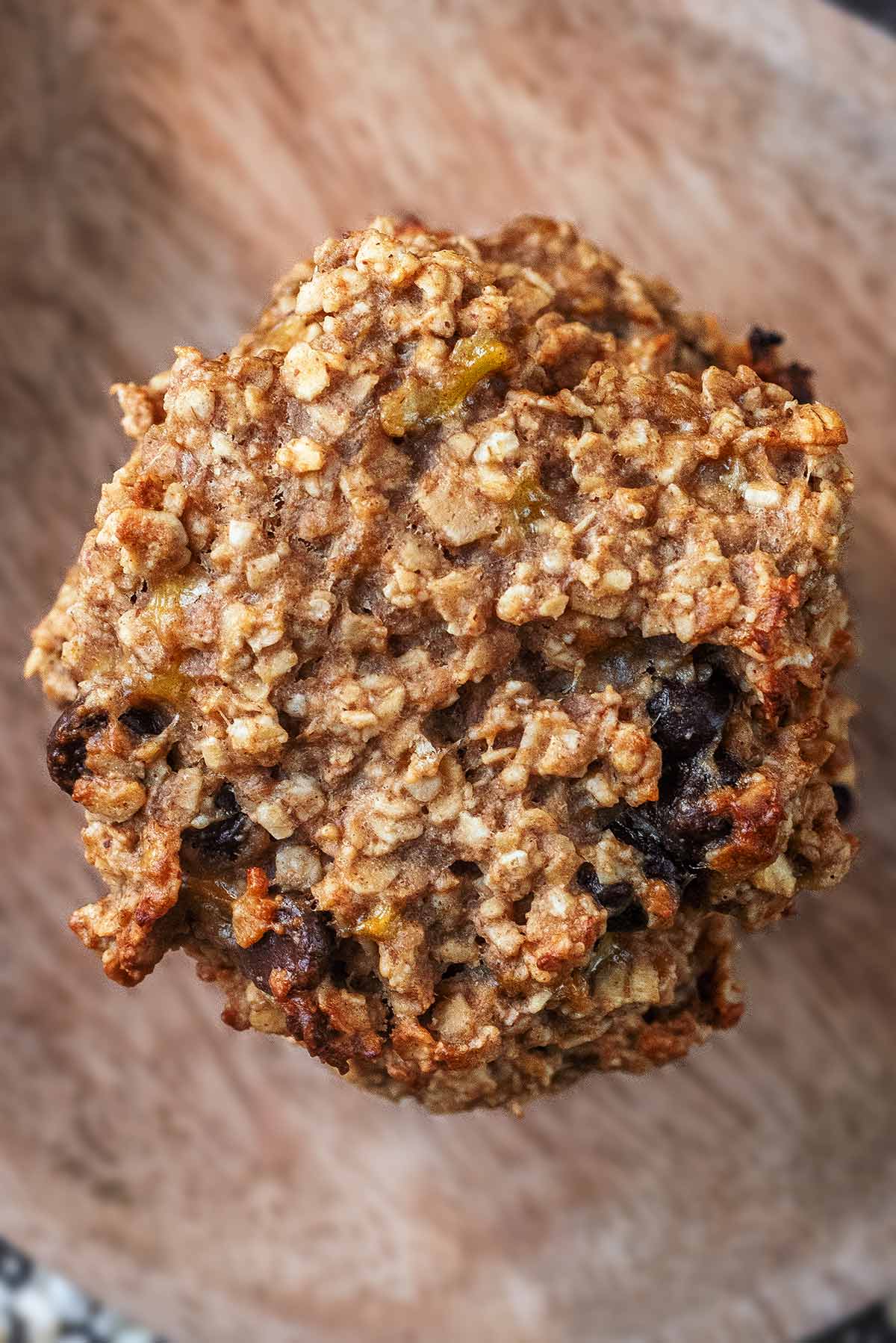 A chocolate chip oat cookie on a wooden surface.