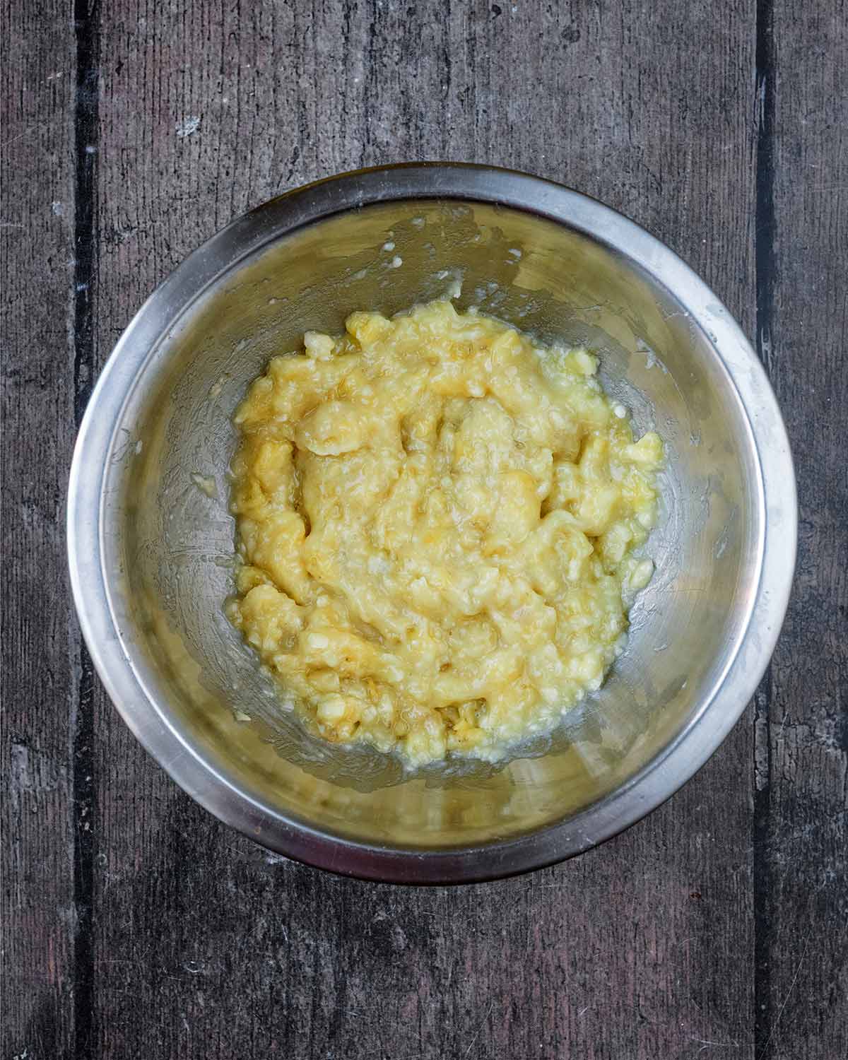 A mixing bowl containing mashed banana.