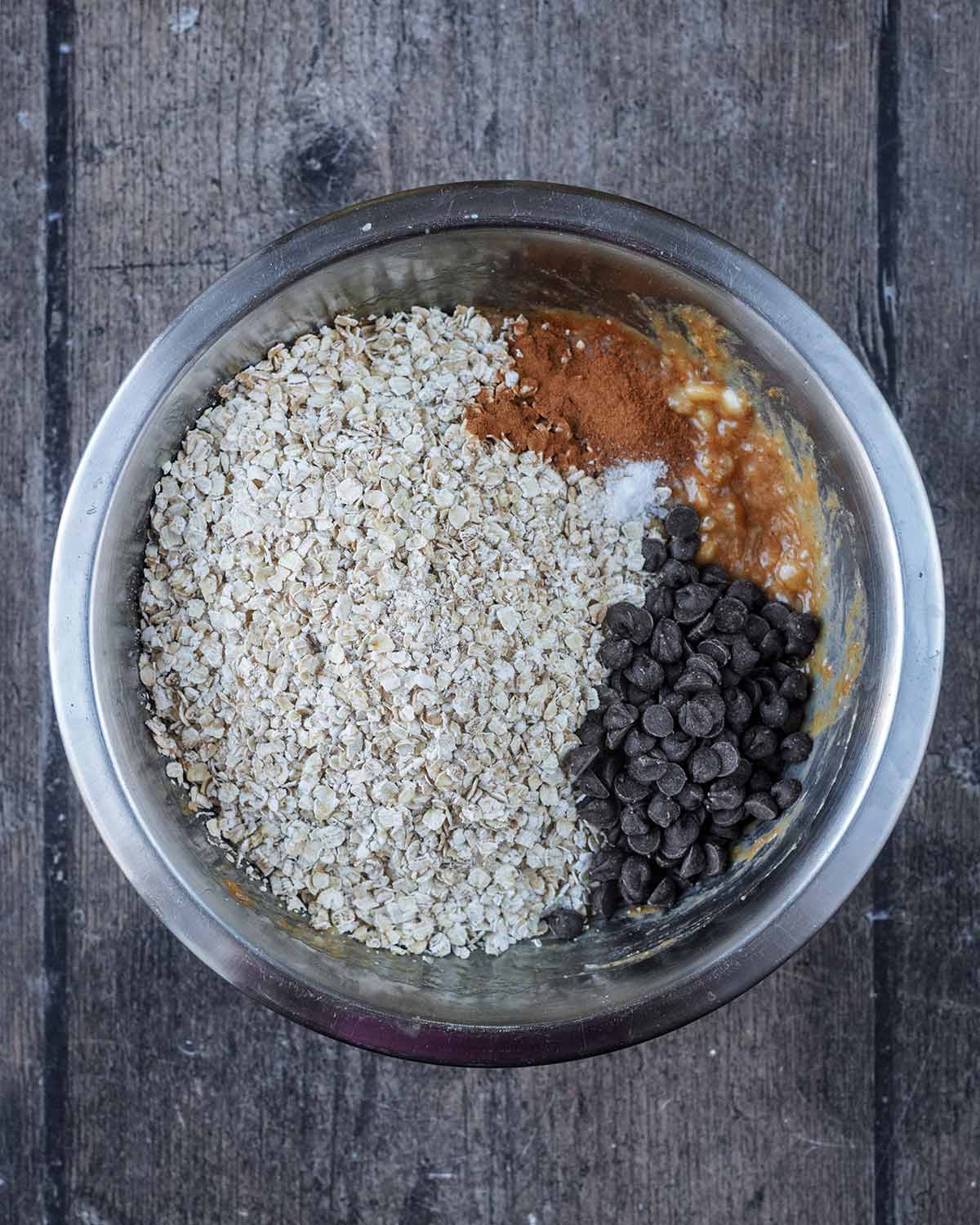 Oats, cinnamon, salt and chocolate chips added to the mixing bowl.