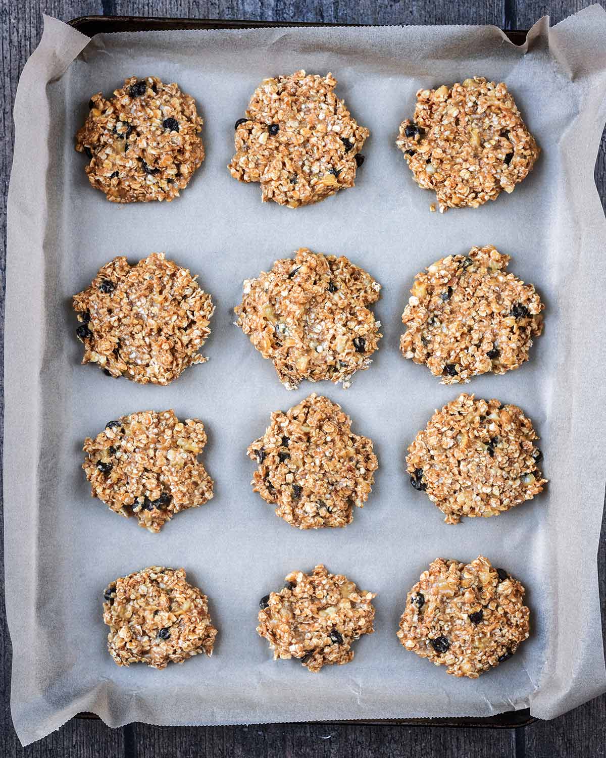 Twelve uncooked cookies on a lined baking sheet.
