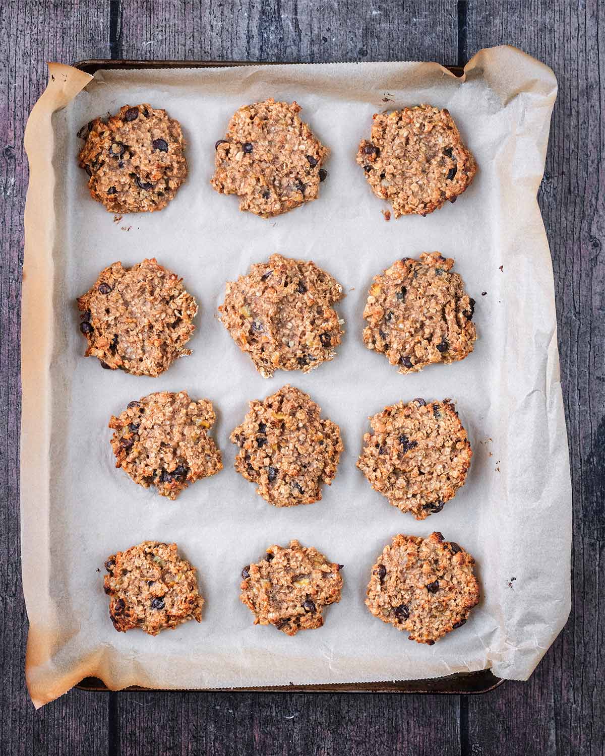 Twelve baked cookies on a lined baking sheet.