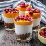 Four small glasses filled with healthy mango cheesecake.