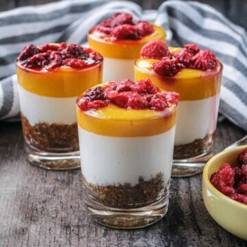 Four small glasses filled with healthy mango cheesecake.