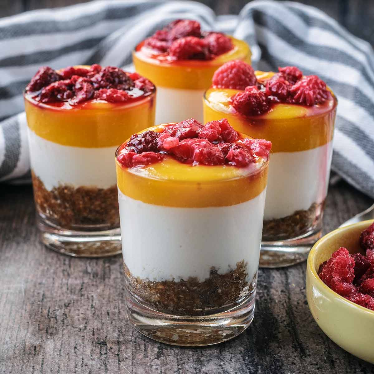 Four small glasses filled with healthy mango cheesecake.