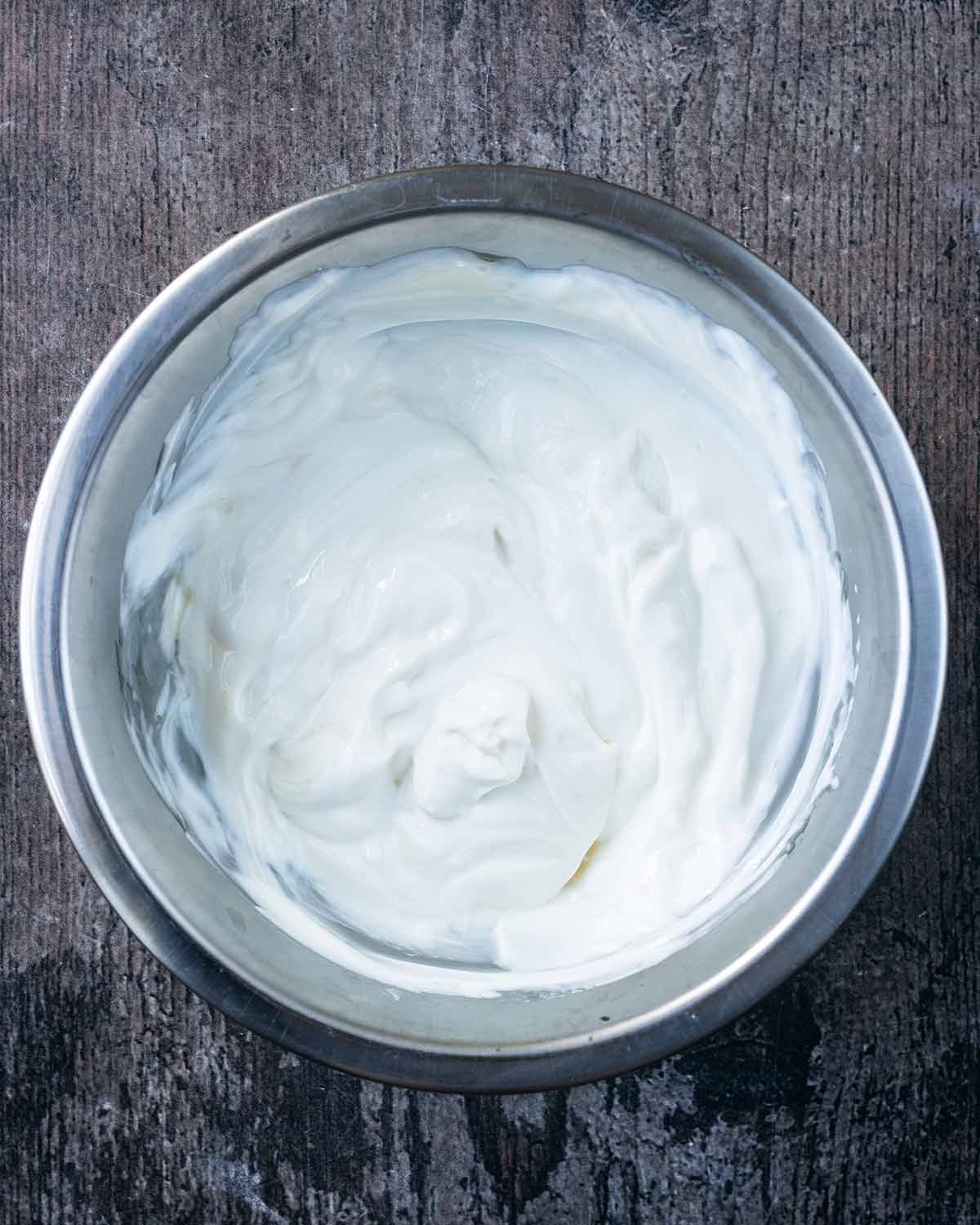 A mixing bowl containing yogurt, cream cheese and honey.