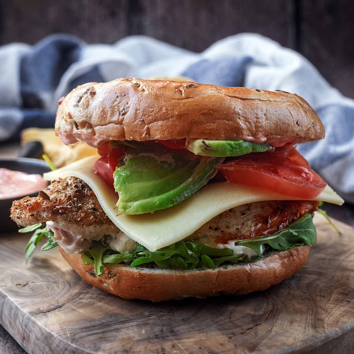 A high protein chicken bagel on a wooden board.