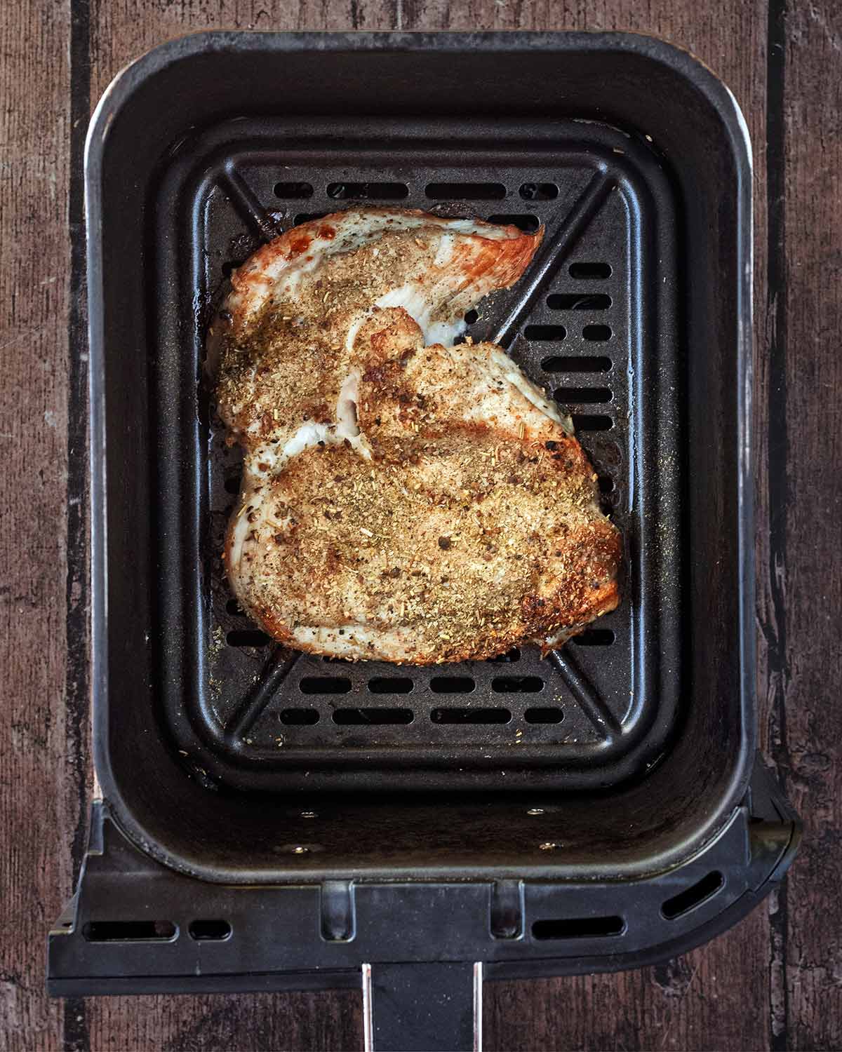 Cooked chicken breast in an air fryer basket.