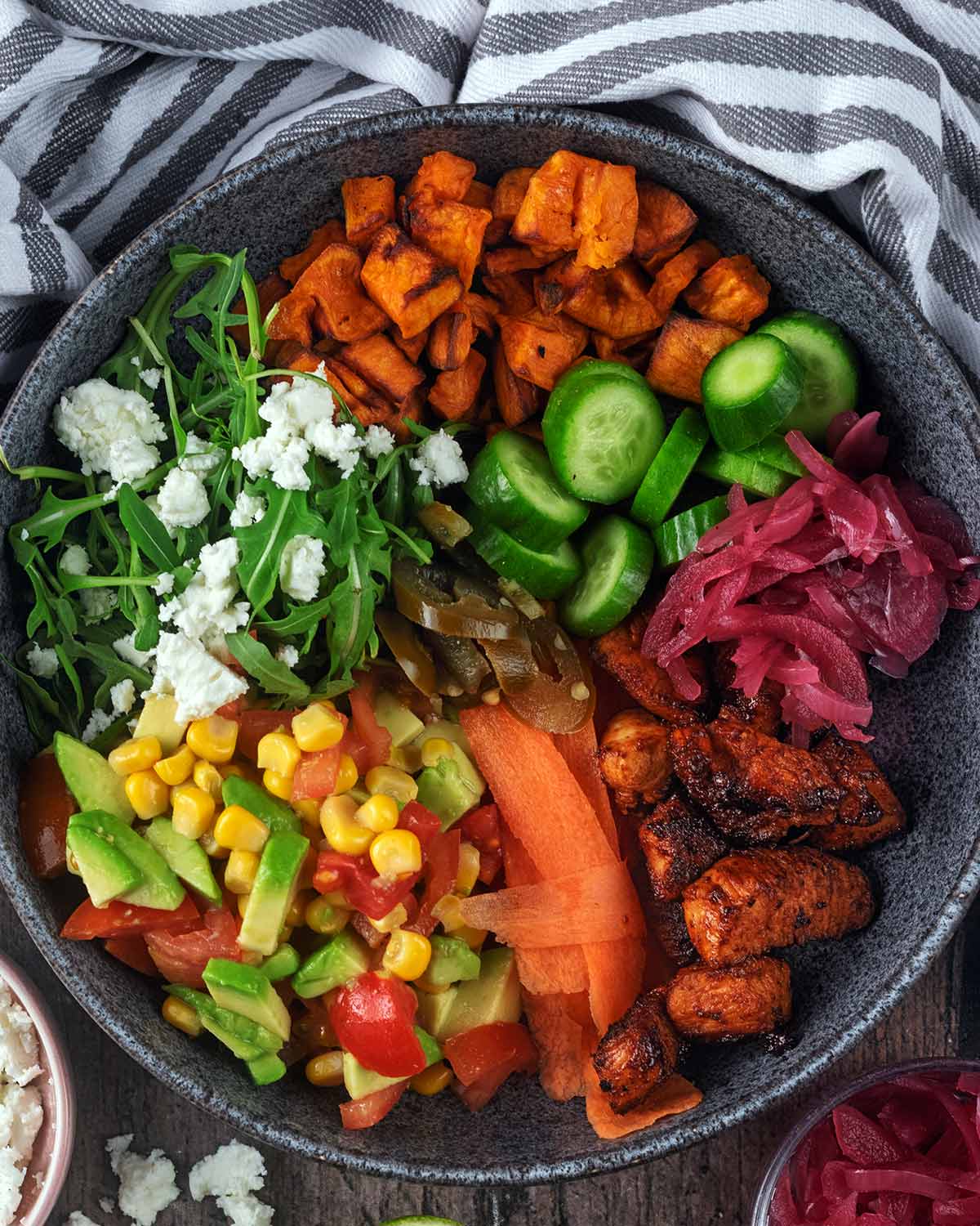 Cooked chicken cubes, salad, salsa and cheese in a grey bowl.