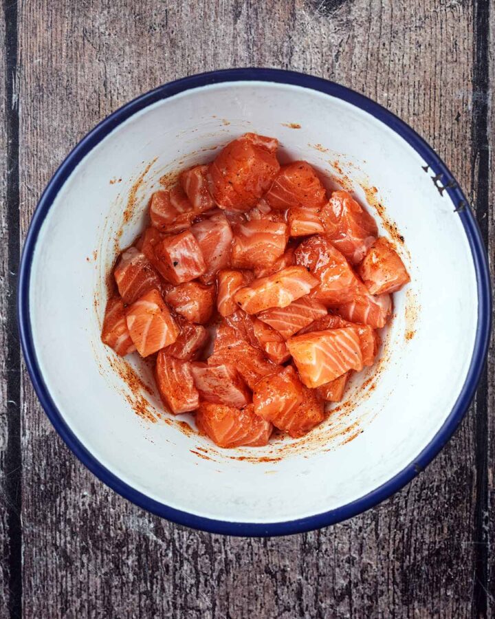 A bowl of salmon chunks coated in honey and spices.