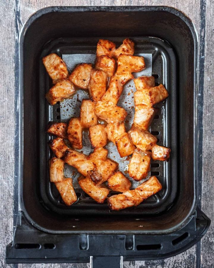 Cooked salmon chunks in the air fryer basket.