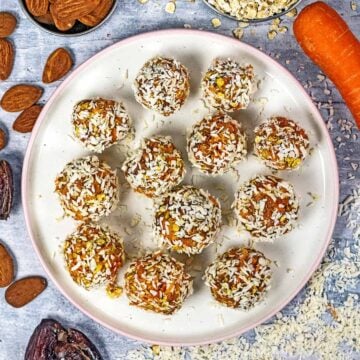Twelve raw carrot cake bites on a small round plate.