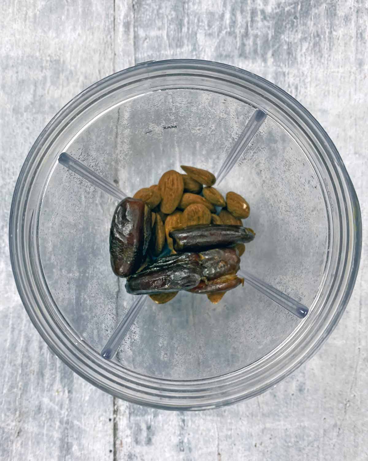 Dates and almonds in a small blender jug.