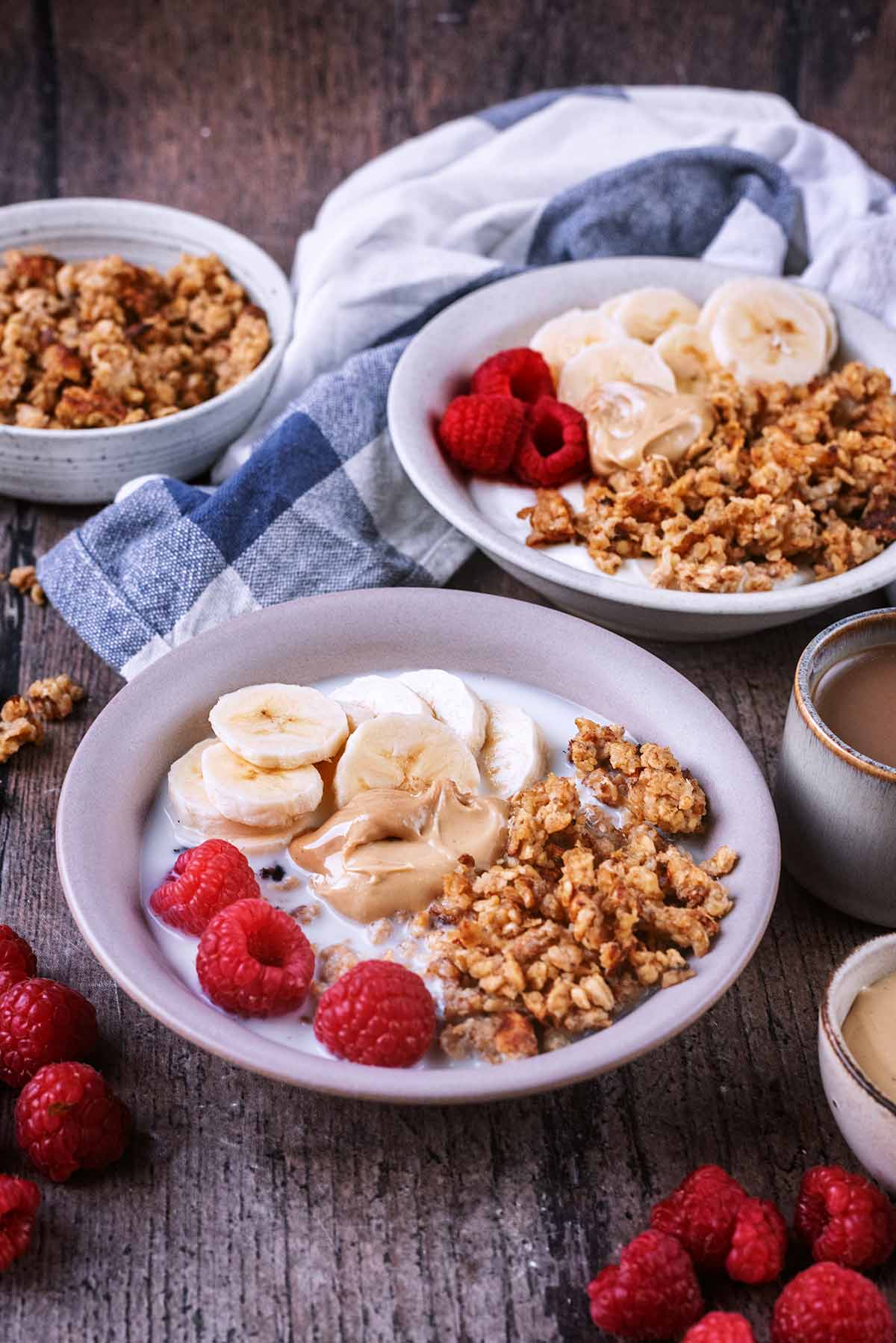 Two bowls of oats, berries and nut butter surrounded  by more berries.