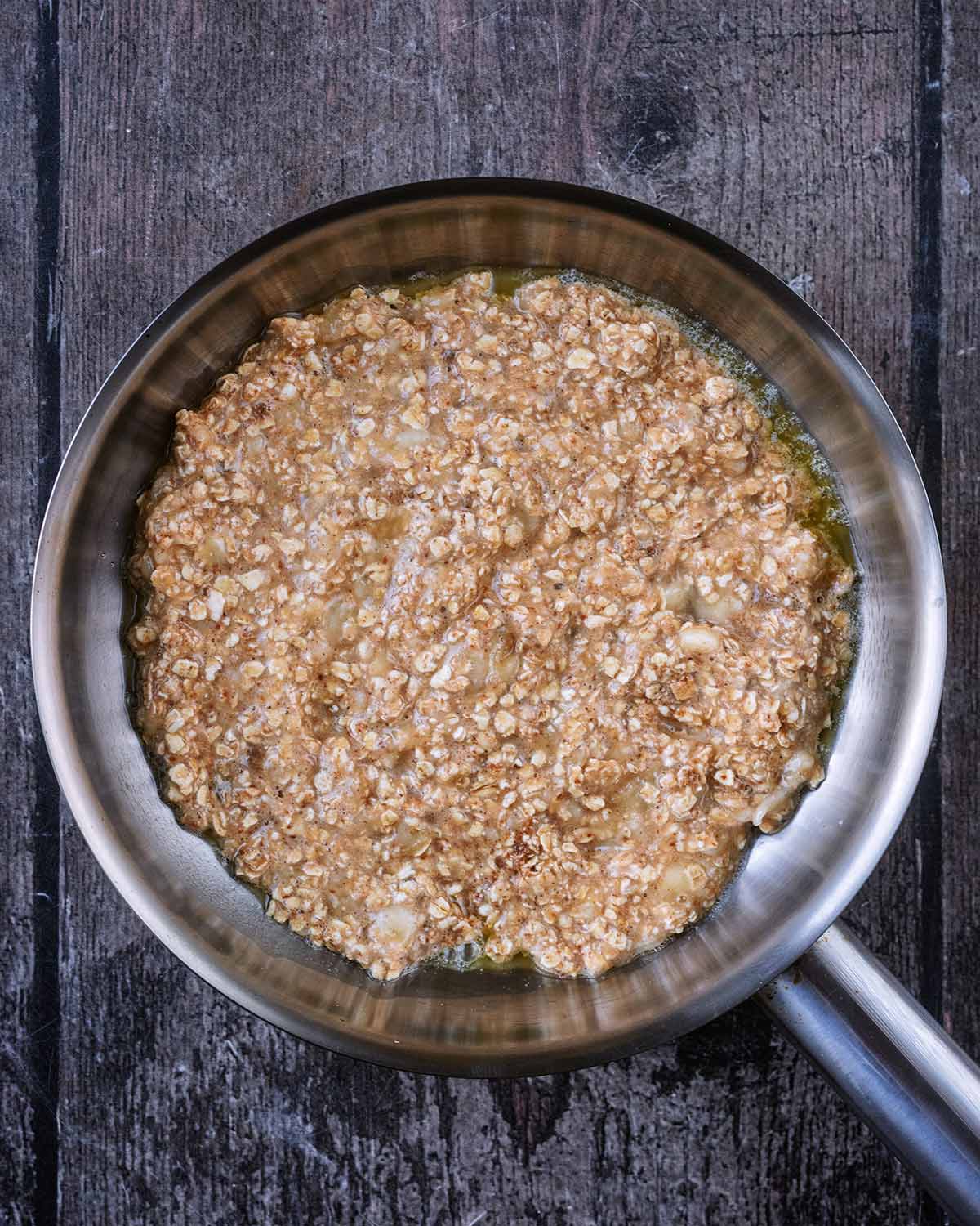 The oat mixture spread out in a frying pan.