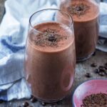 A tall glass of coffee smoothie with another glass in the background.