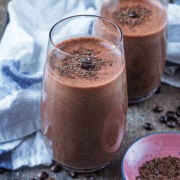 A tall glass of coffee smoothie with another glass in the background.