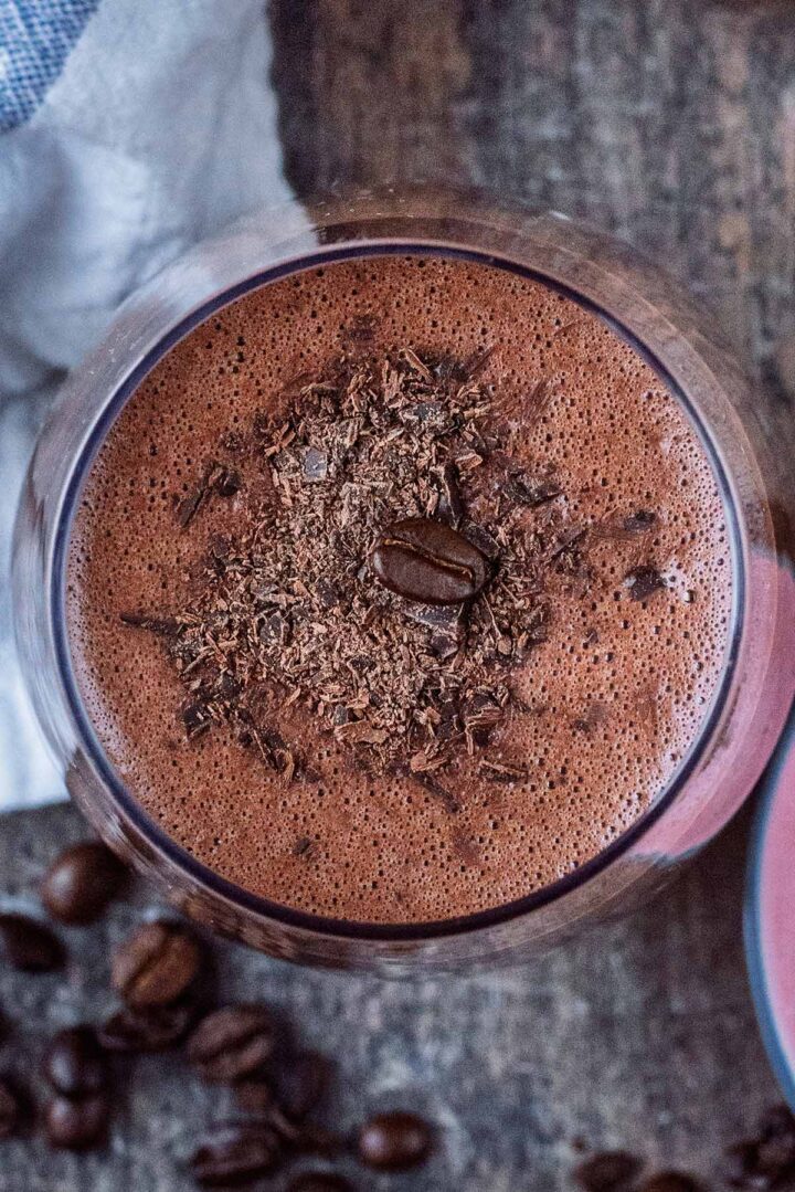 Grated chocolate and a single coffee bean on top of a smoothie.