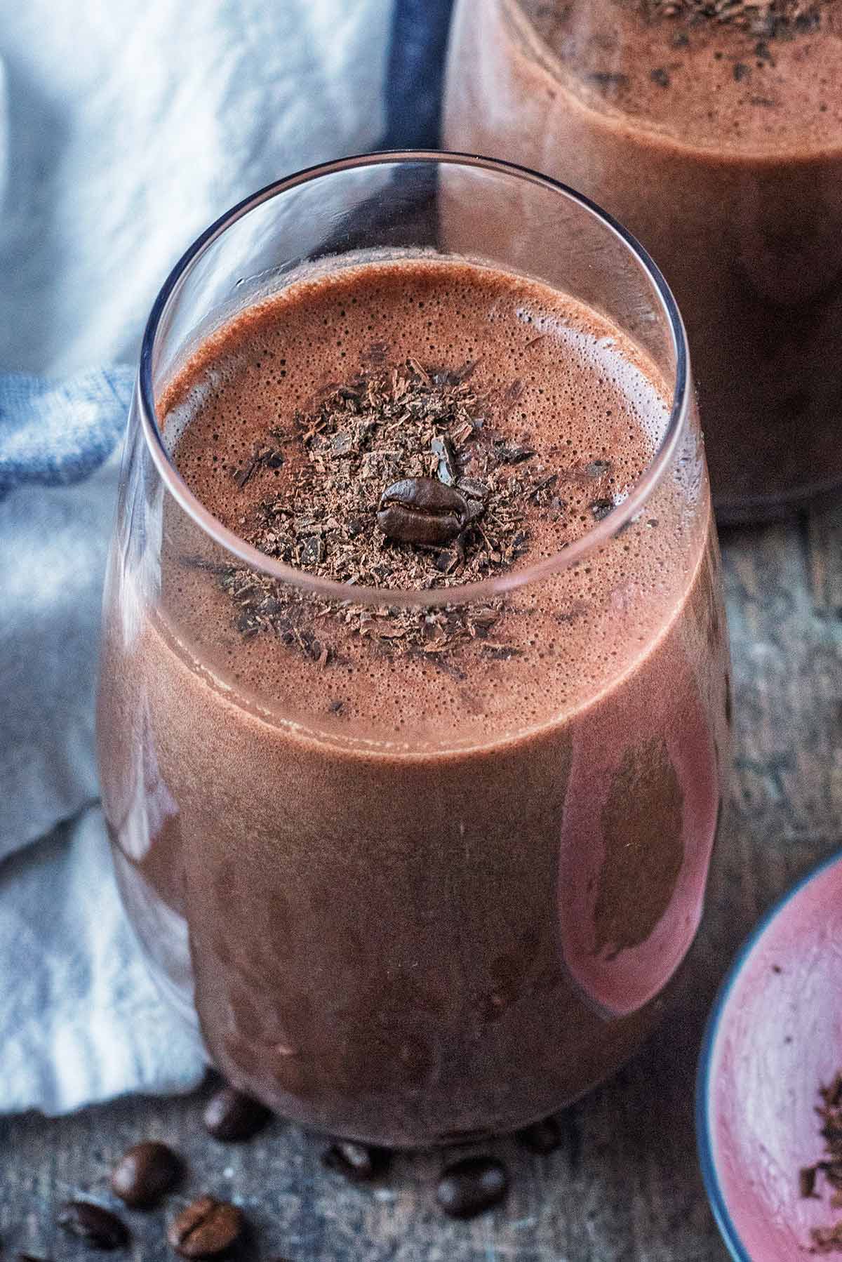A tall glass containing a brown smoothie.