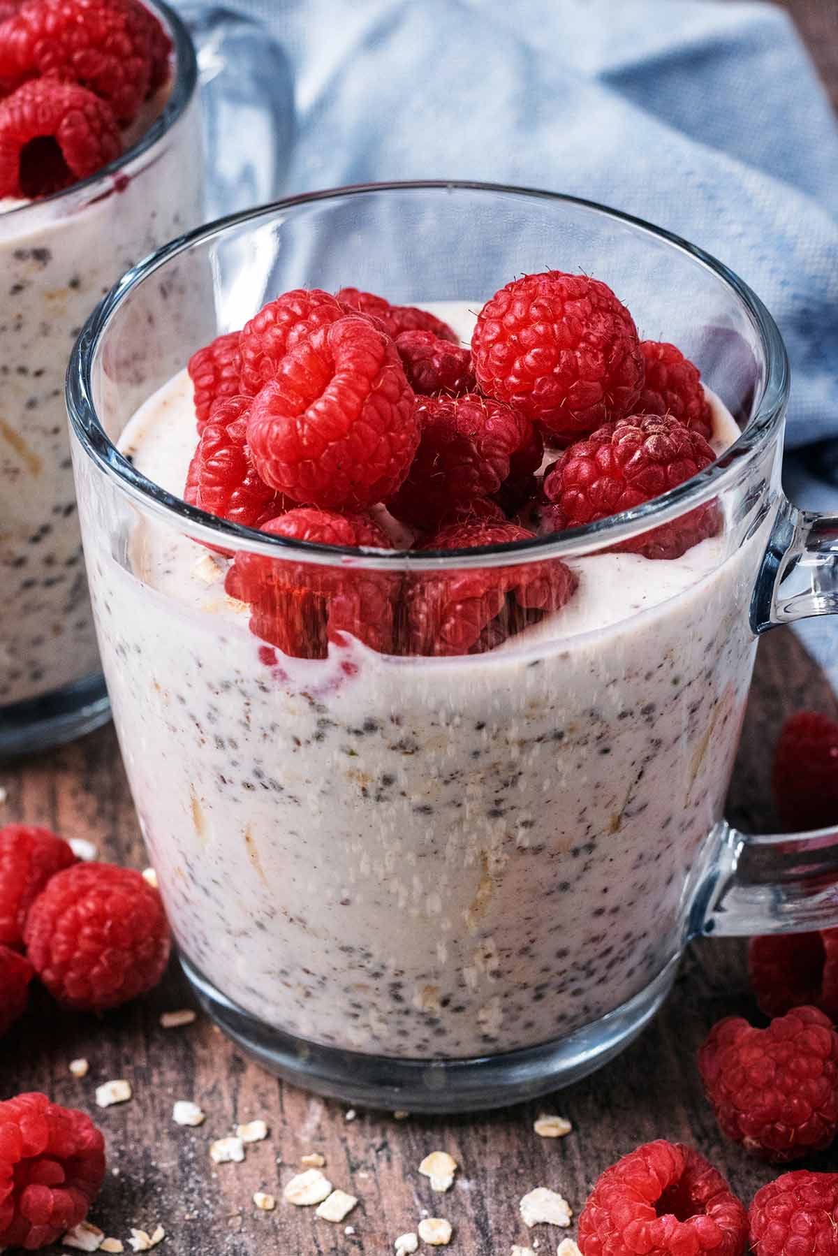 A glass full of overnight oats and raspberries.