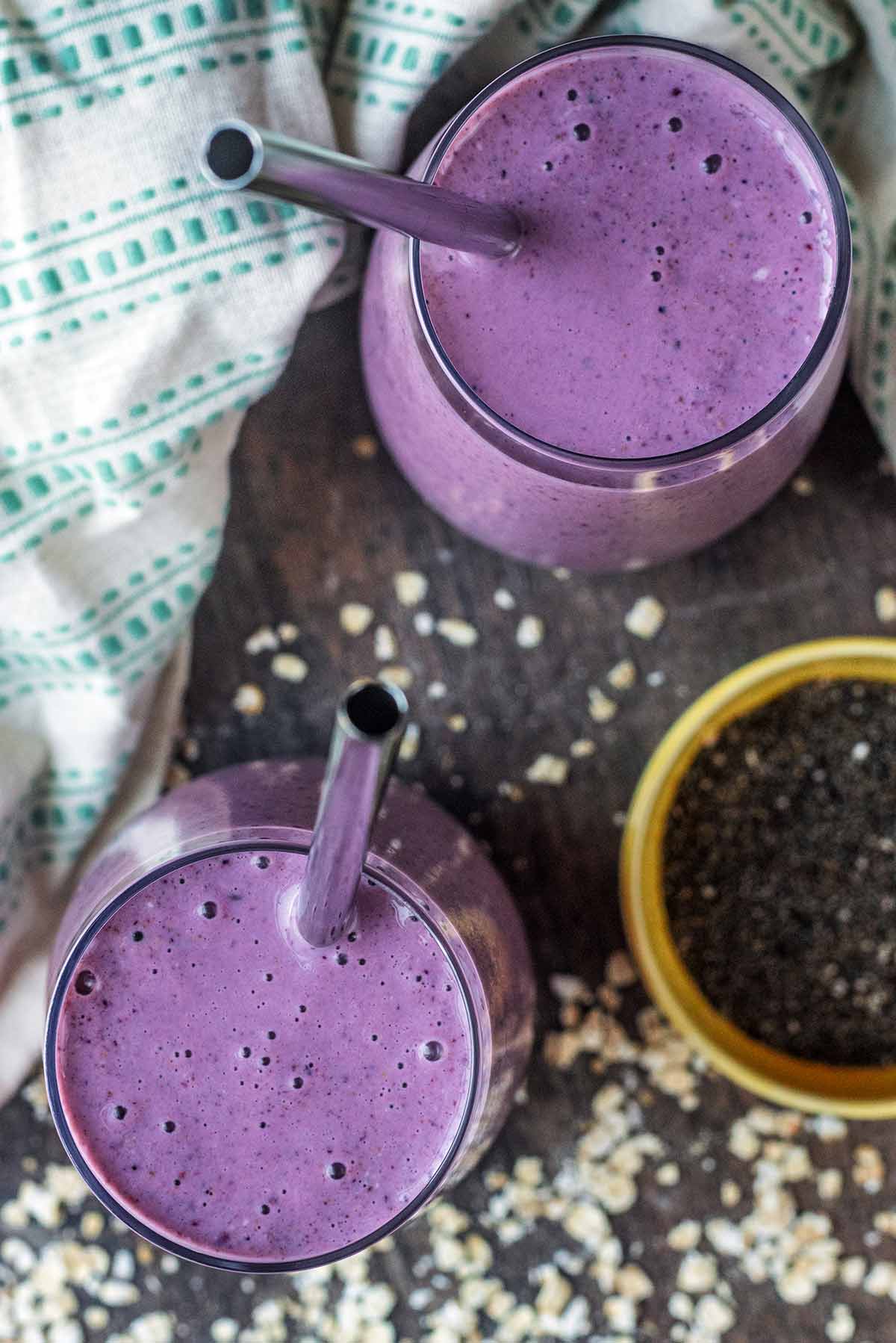 Two glasses of a purple coloured smoothie as viewed from above.