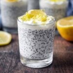 Lemon chia pudding in a glass in front of a lemon half.