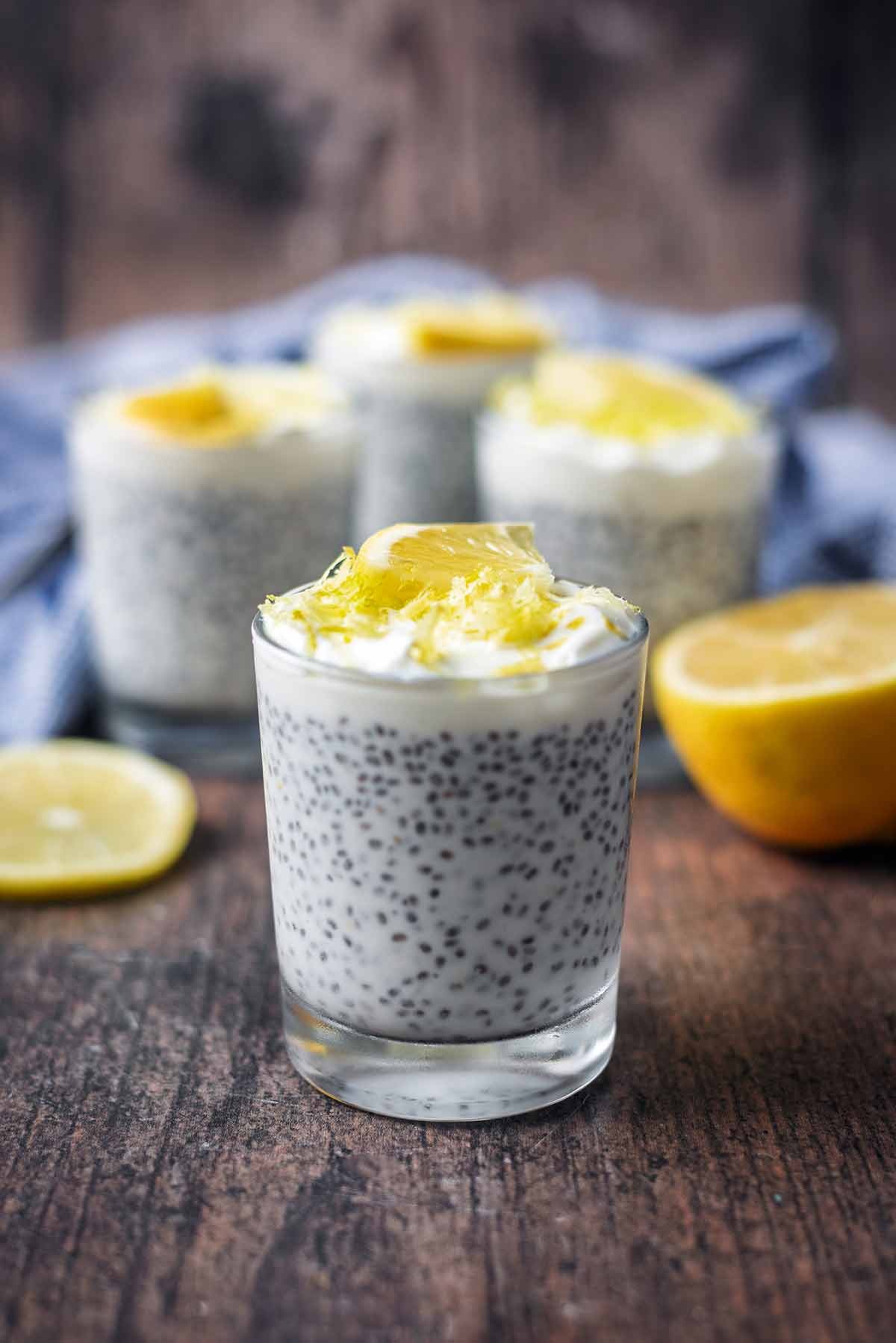 A glass of chia pudding with three more glasses of chia pudding in the background.