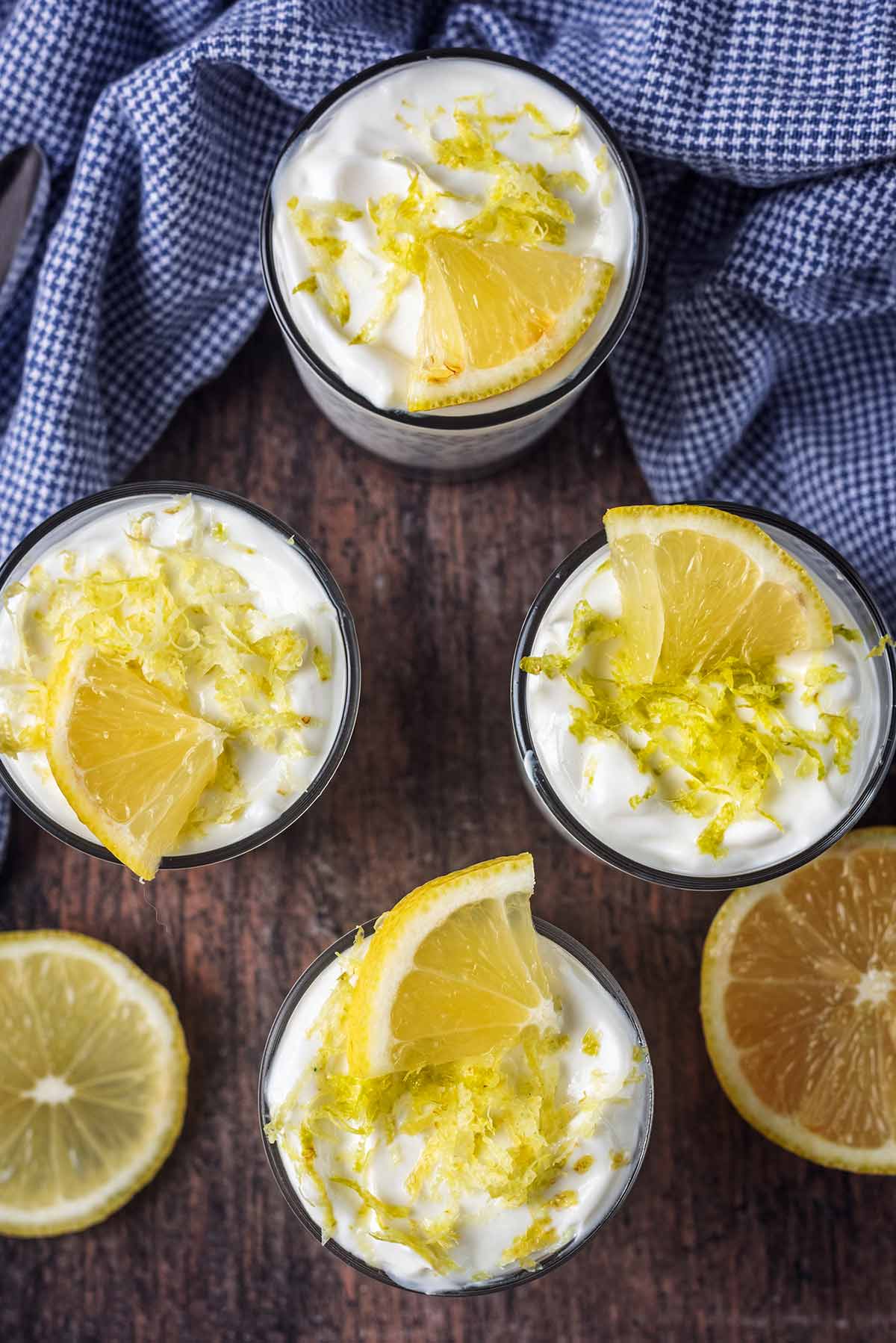 Four glasses of chia pudding toped with a quarter lemon slice and some lemon zest.