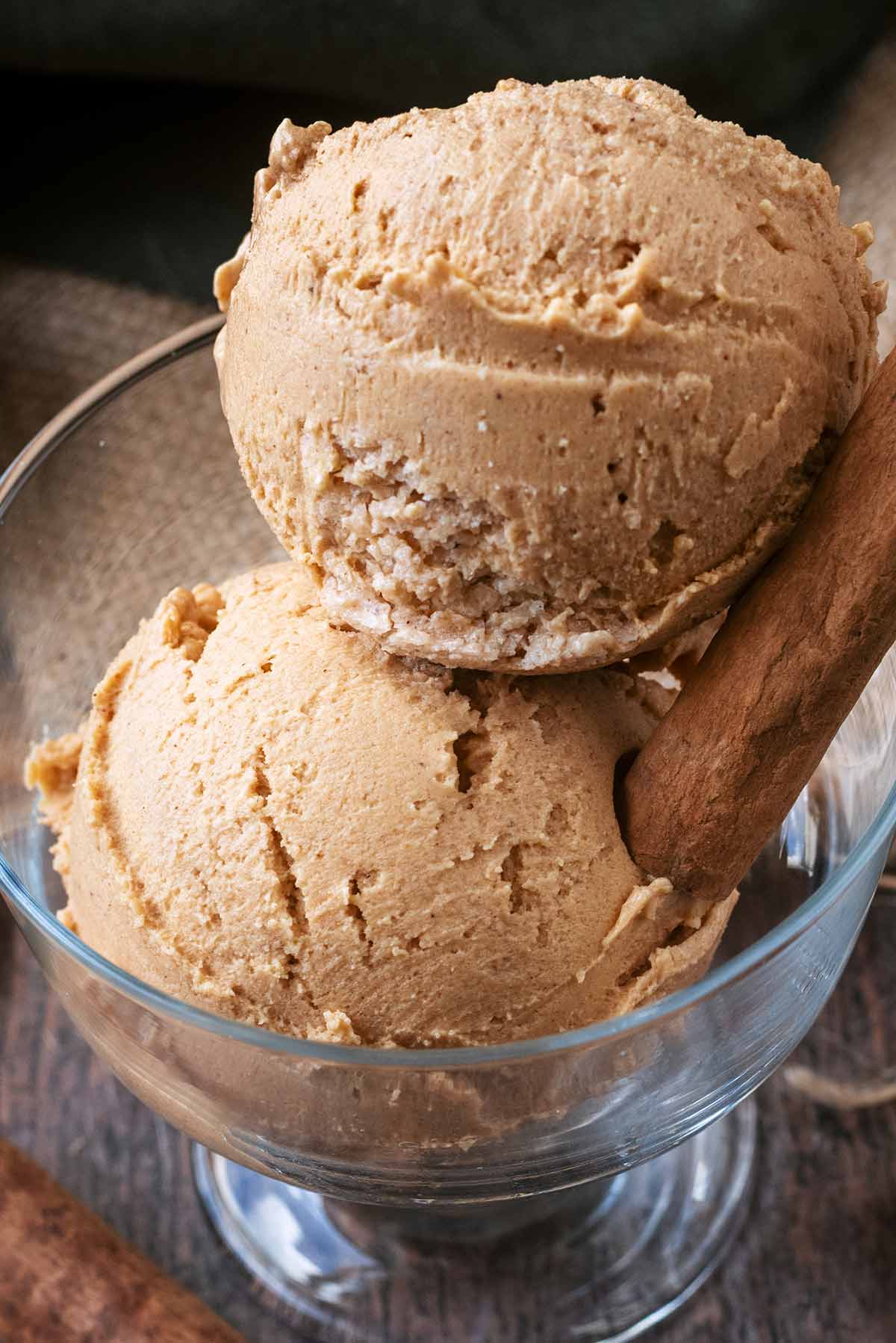 Two balls of pumpkin ice cream with a cinnamon stick.