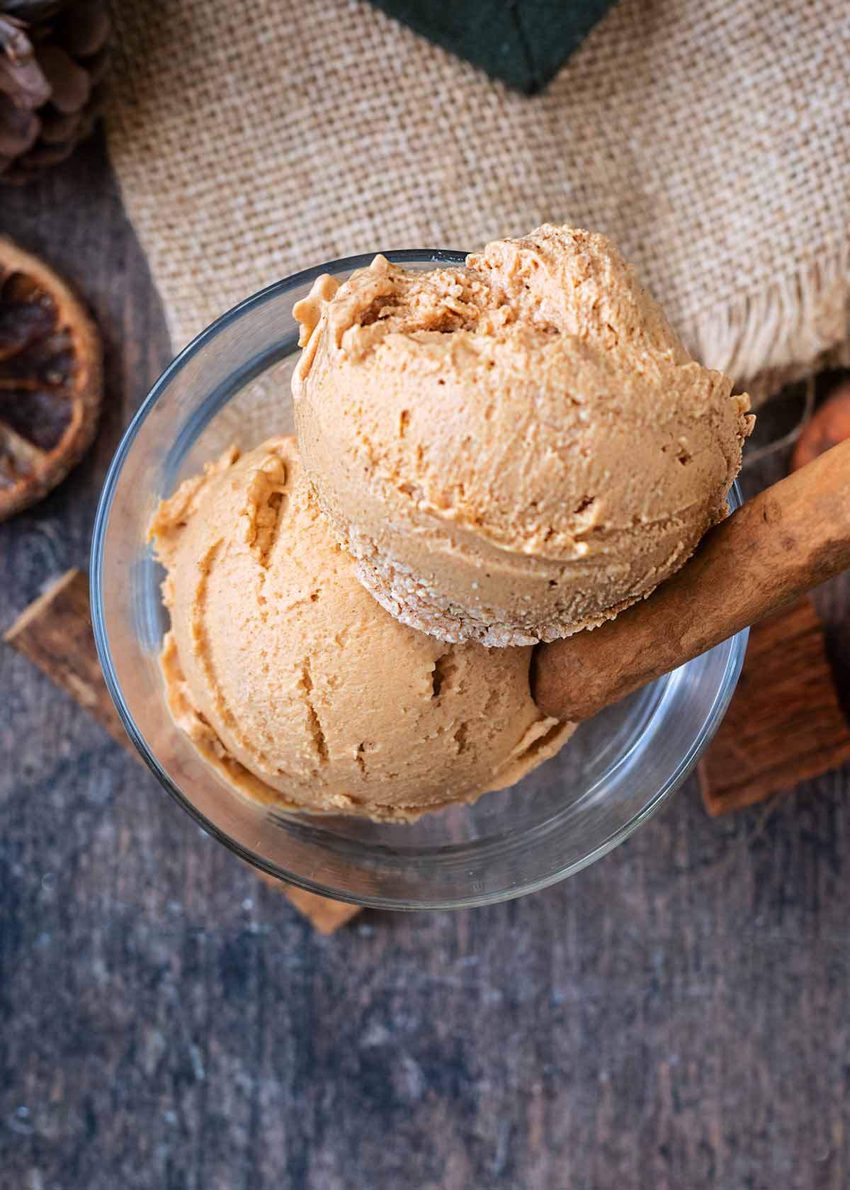 Two balls of pumpkin ice cream in a serving glass as viewed from above.