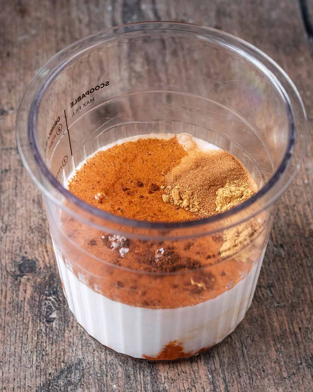 Milk, yogurt, pumpkin puree and spices in a Ninja Creami tub.