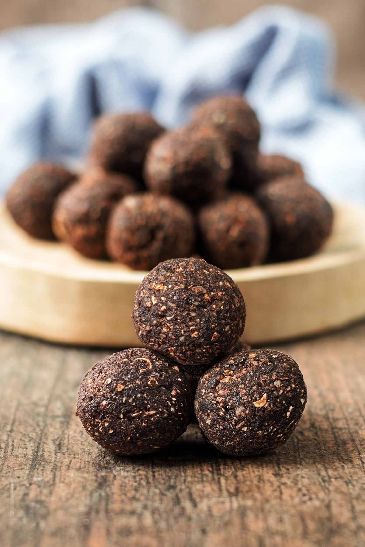 A pyramid of chocolate energy bites in front of a serving board of more bites.