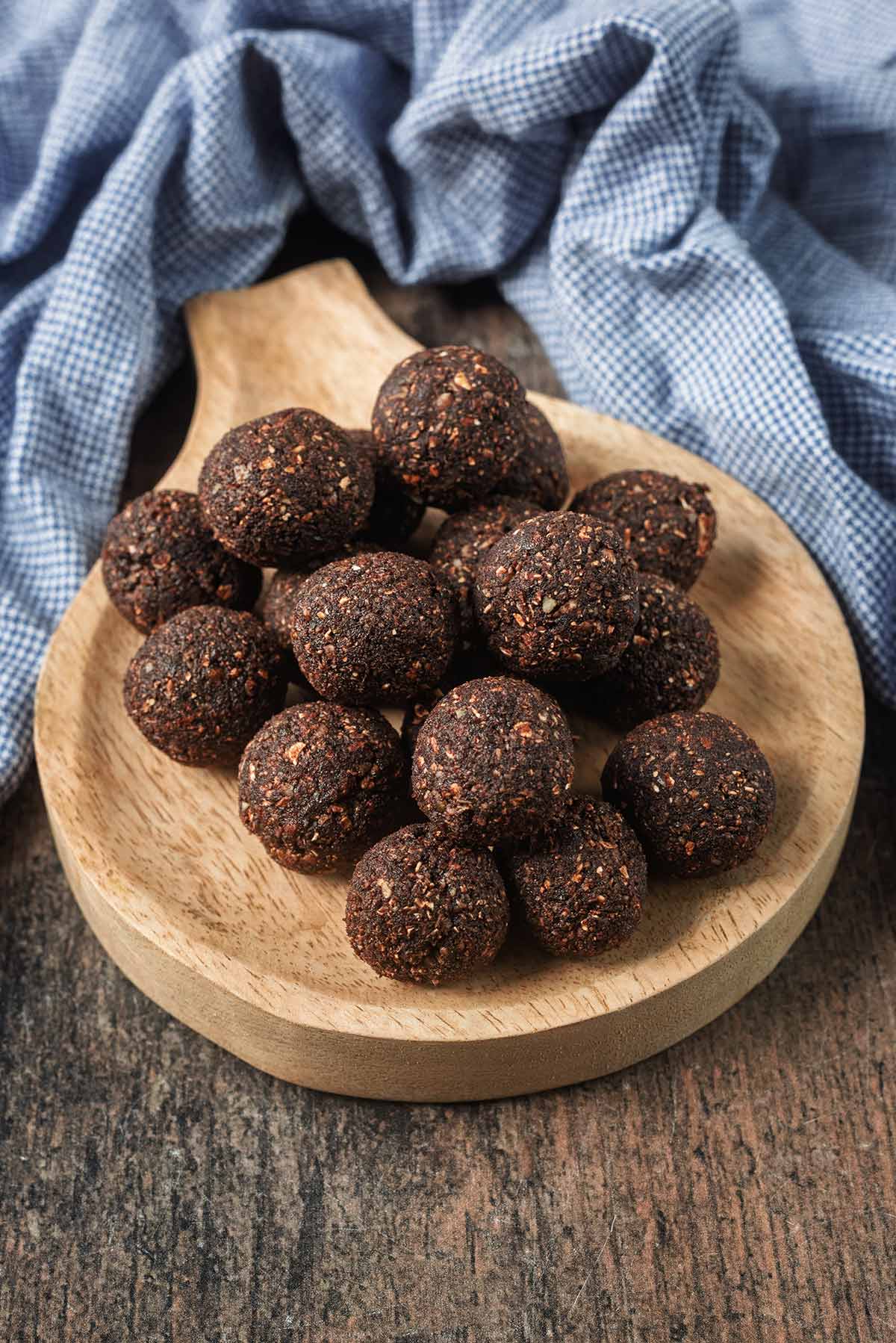A pile of chocolate energy balls on a small round serving board.