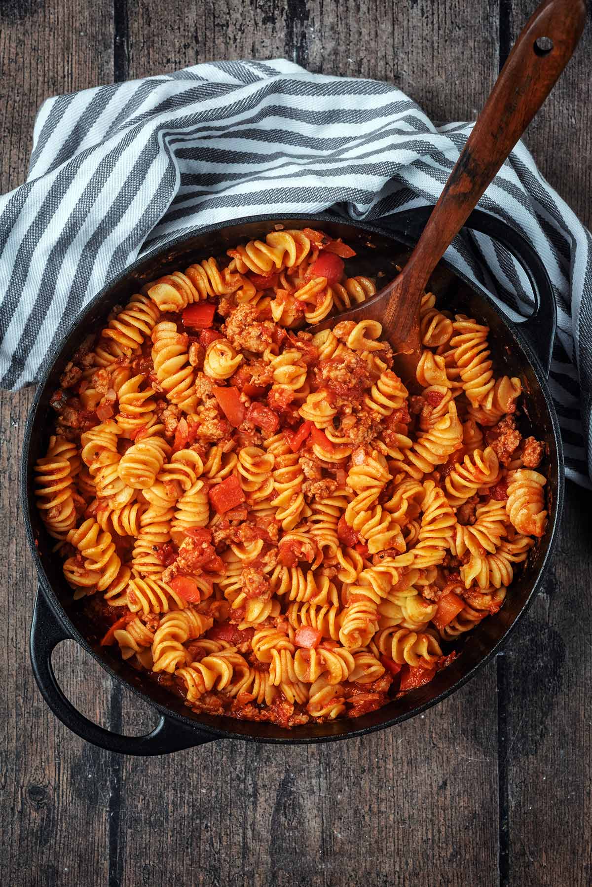 A black cooking pot containing cooked sausage pasta.