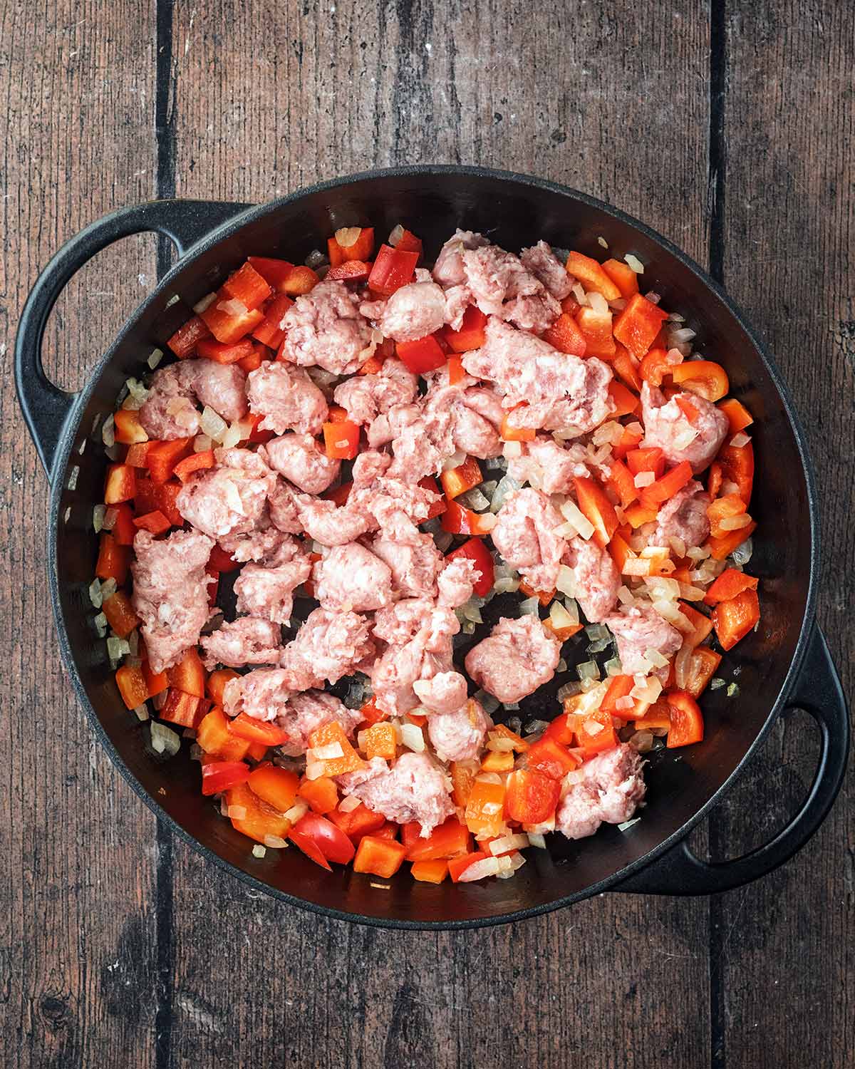 Chopped bell pepper and sausage meat added to the pan.