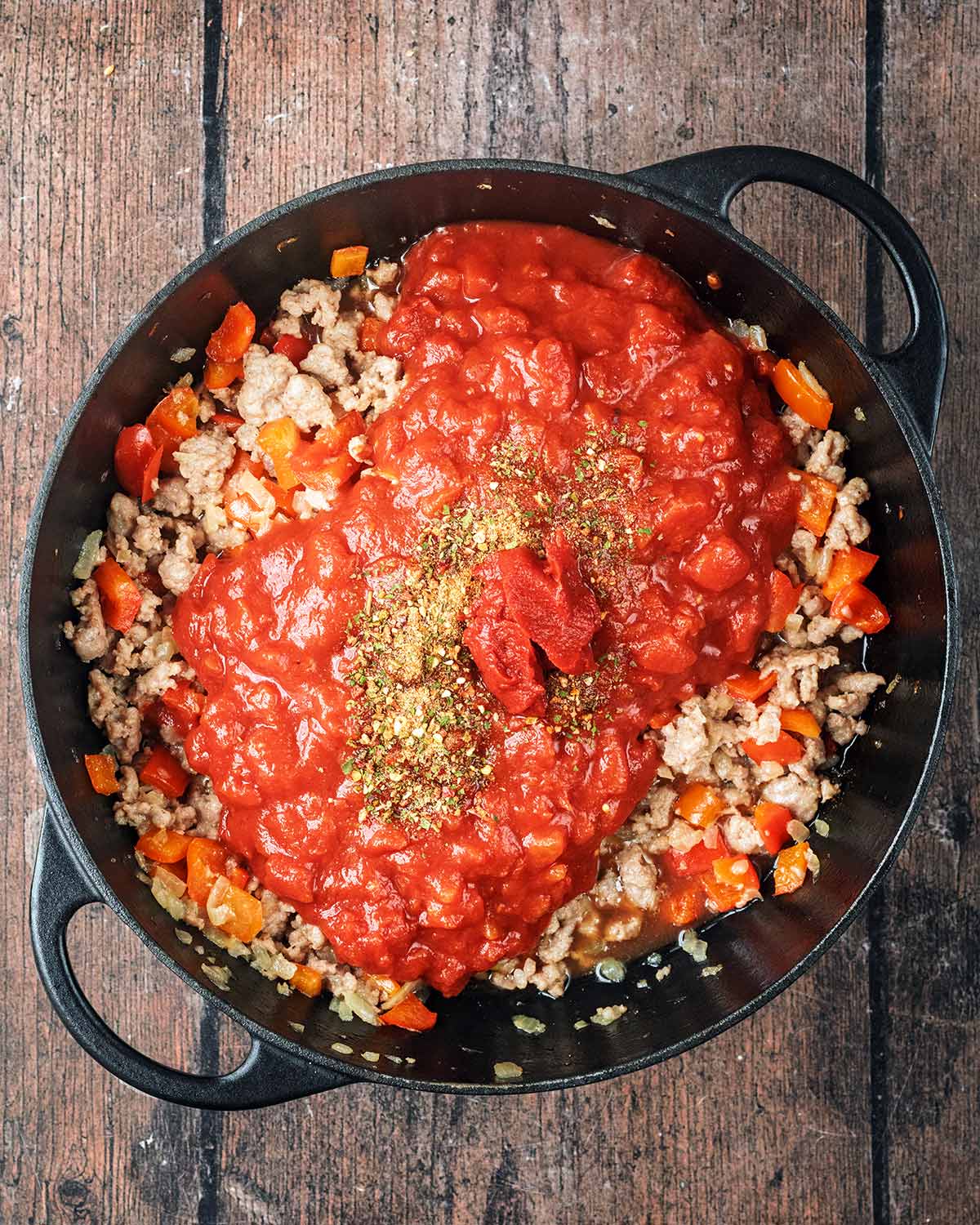Chopped tomatoes, seasoning and tomato pure added to the pan of sausage and peppers.