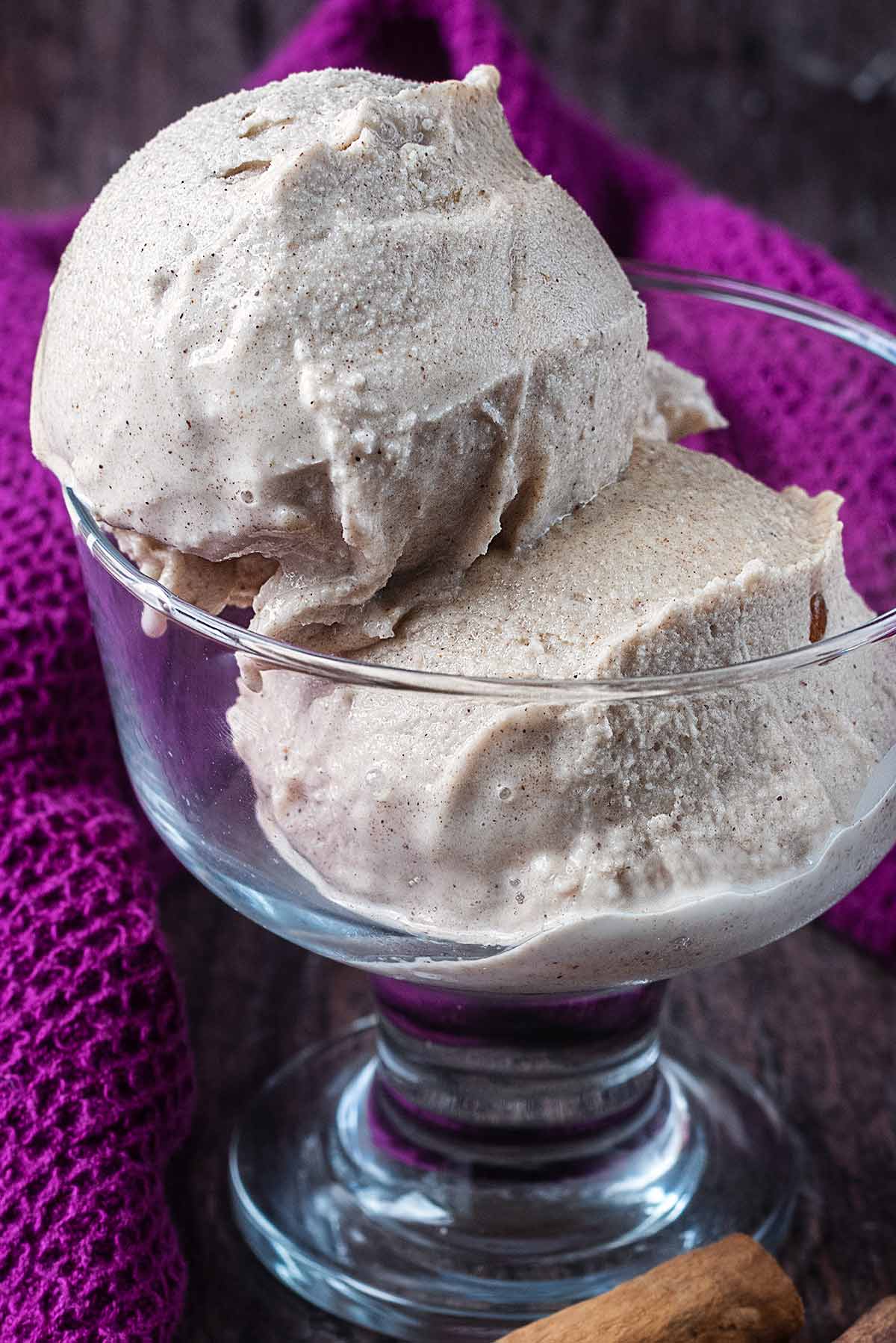 Two balls of ice cream slightly melting in a glass.