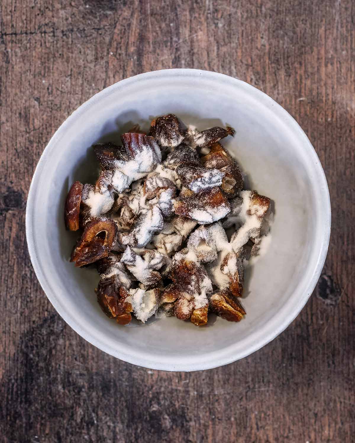 Pitted dates in a bowl with baking soda sprinkled on top.