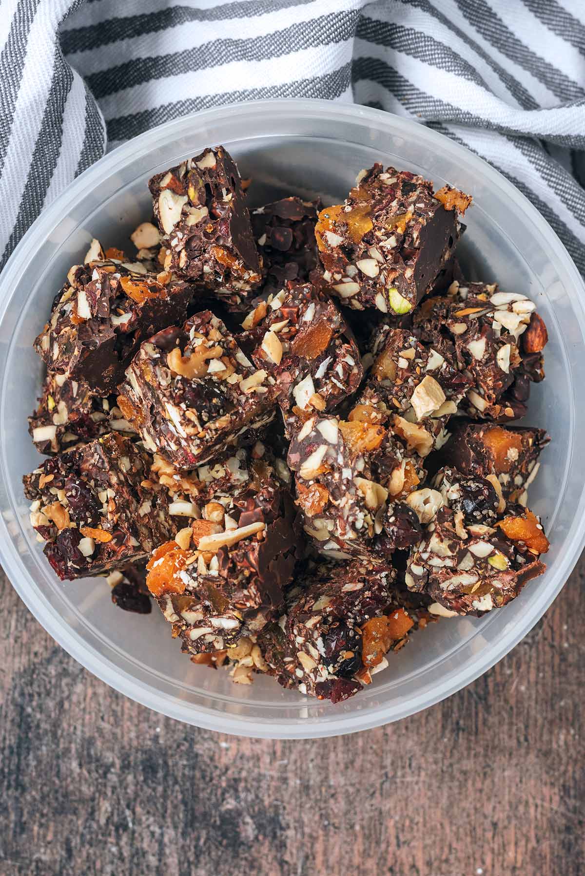 A round plastic container full of cubes of rocky road.