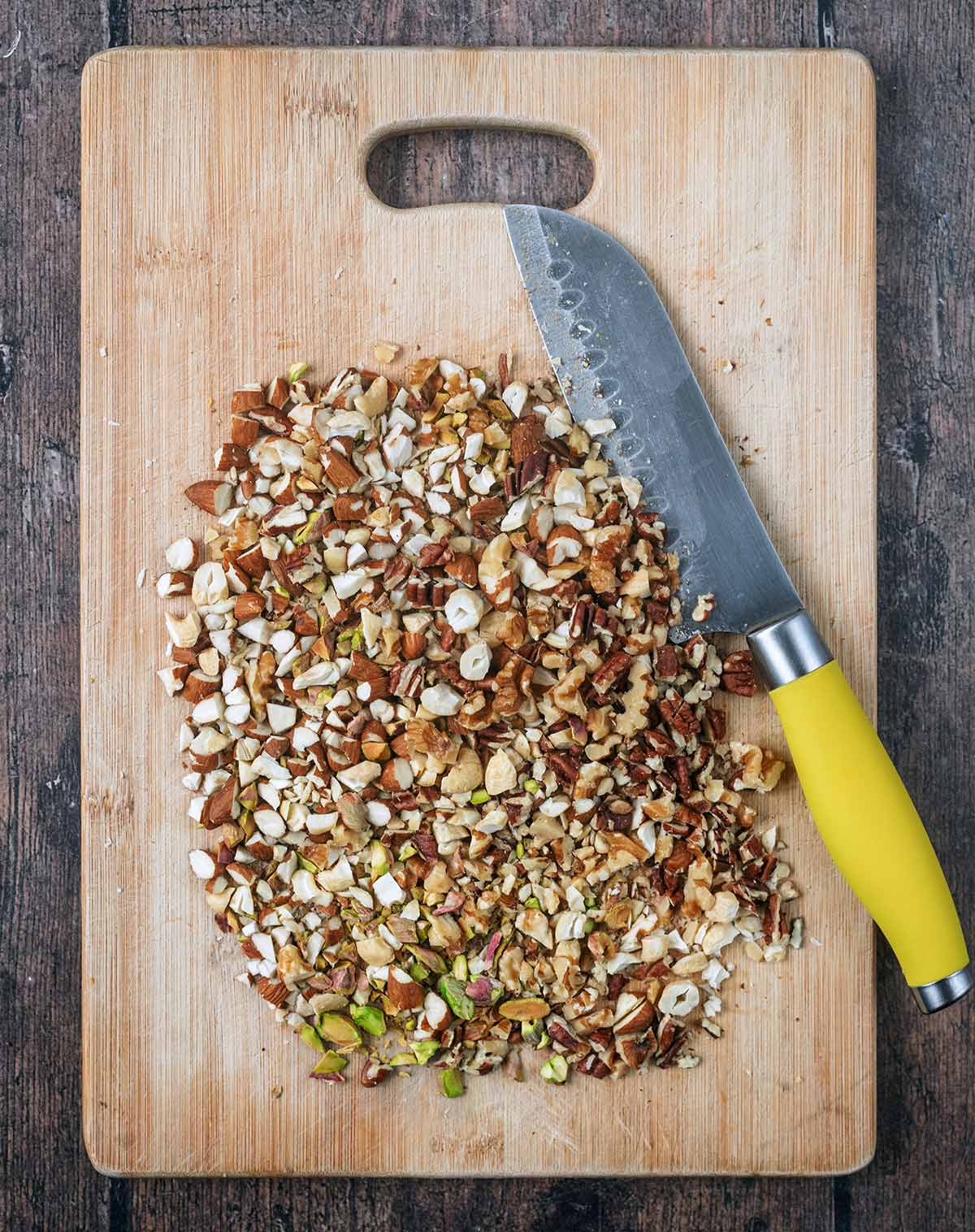 Chopped nuts and a knife on a wooden chopping board.