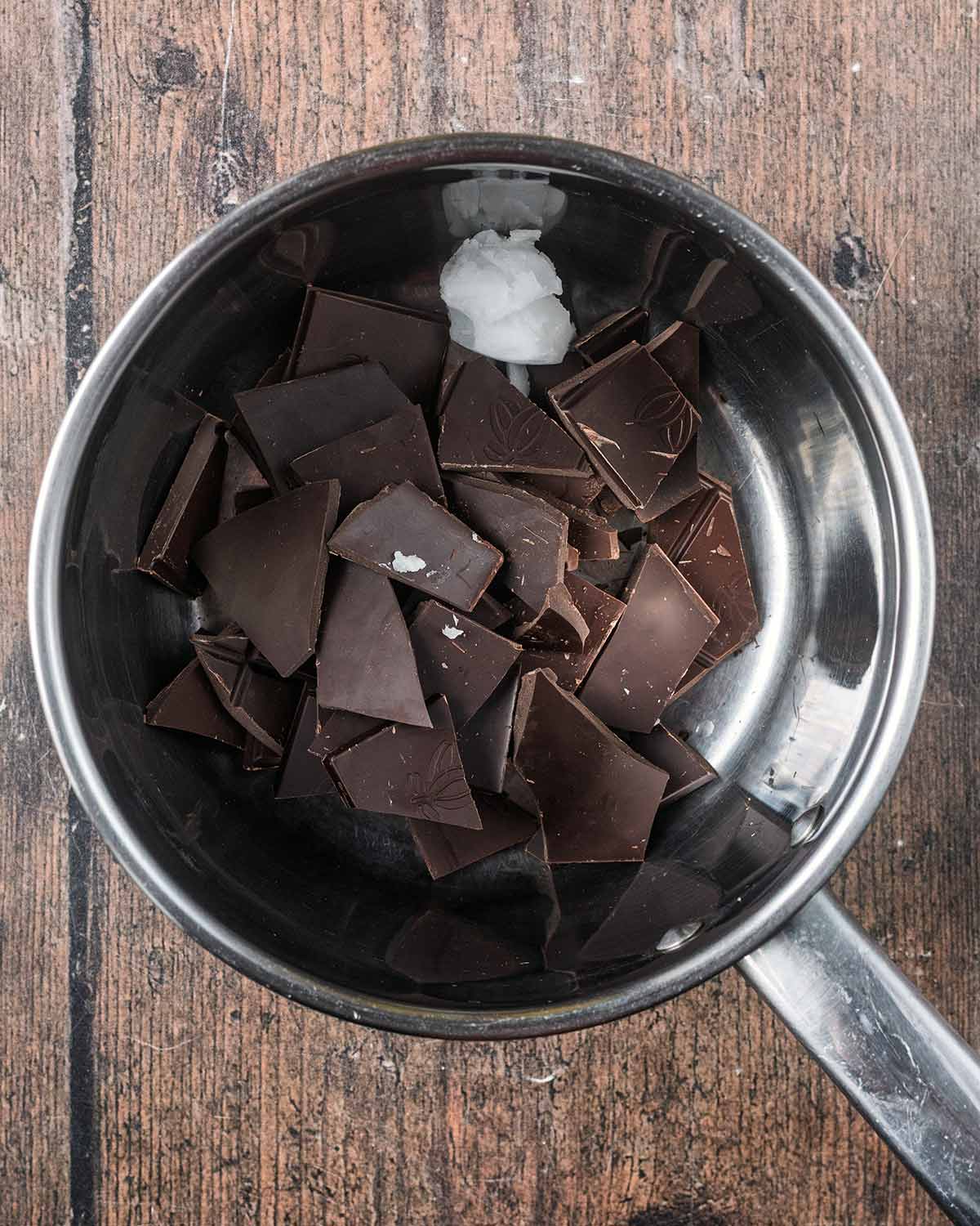 Chunks of dark chocolate and some coconut oil in a saucepan.