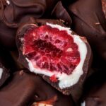 Half a frozen raspberry coated in white chocolate and dark chocolate.