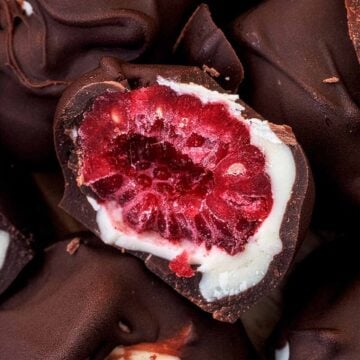 Half a frozen raspberry coated in white chocolate and dark chocolate.