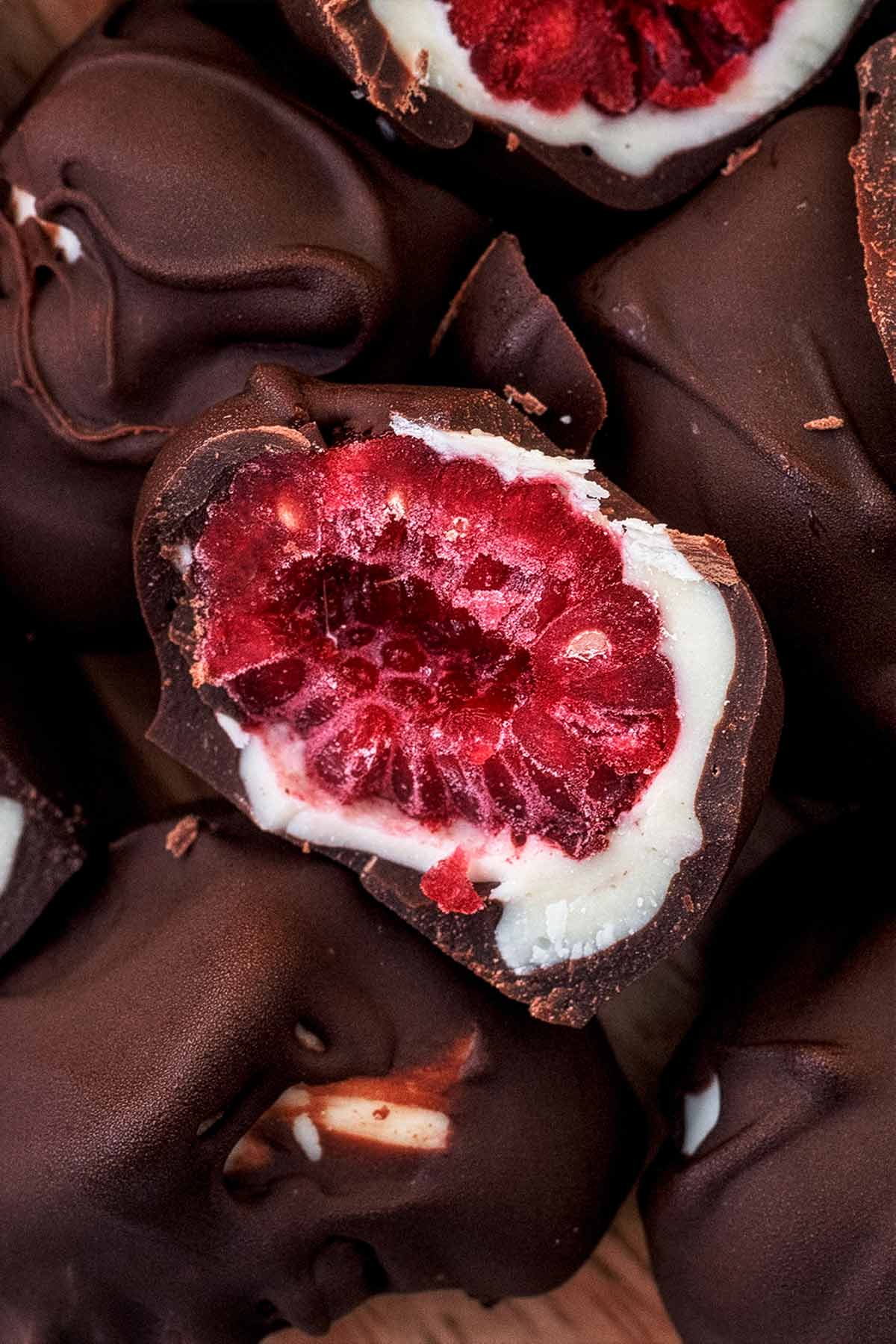 A frozen raspberry coated in white chocolate and dark chocolate that has been cut in half.