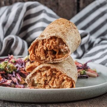Air fryer hunter's chicken wraps stacked up on a plate with some slaw.