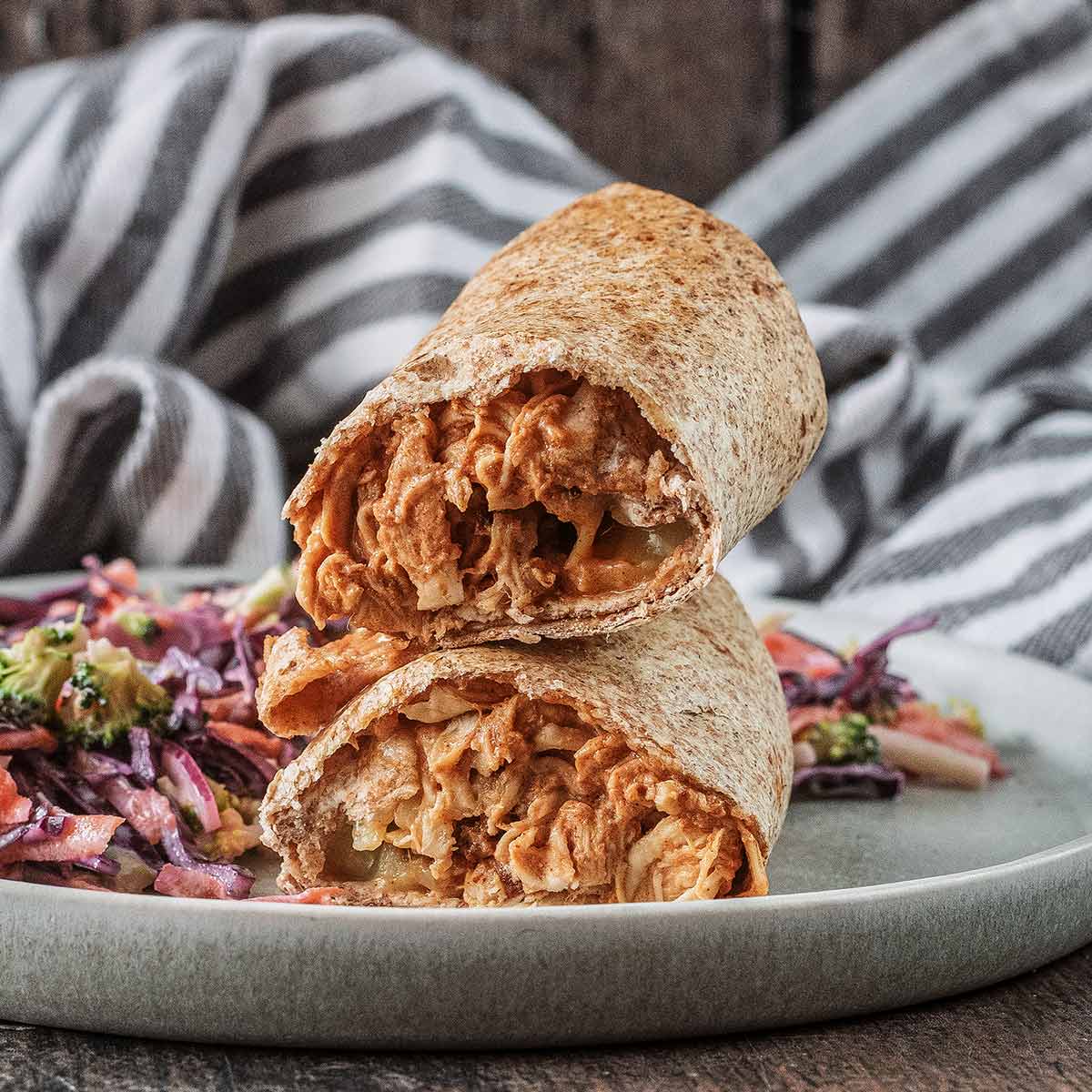 Air fryer hunter's chicken wraps stacked up on a plate with some slaw.